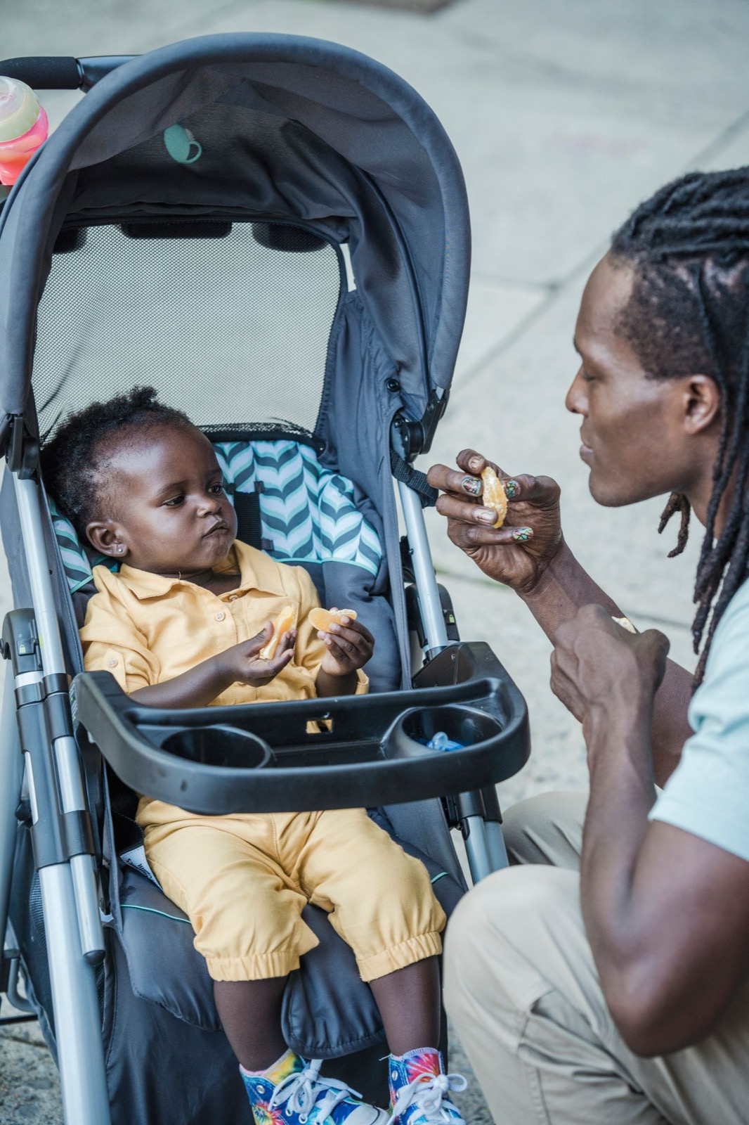 Far mater en smilende baby som sitter i barnevognen